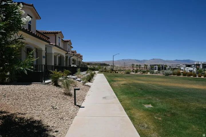 Row of stucco townhomes with red tile roofs and arched entryways