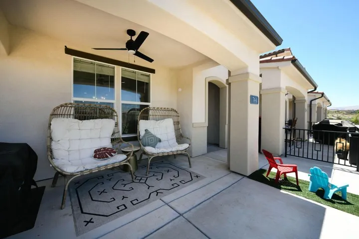 Covered patio with concrete flooring, accented by exterior columns, a mounted ceiling fan, and architectural windows