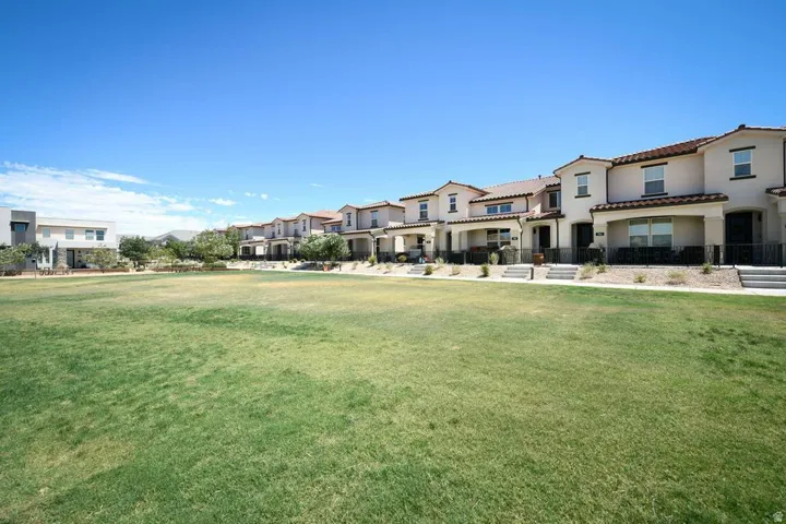 Expansive green space fronting a row of residences with stucco exteriors and tile roofs