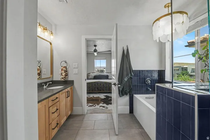 Modern bathroom featuring a single vanity with natural wood cabinetry, a dark countertop, and an undermount sink