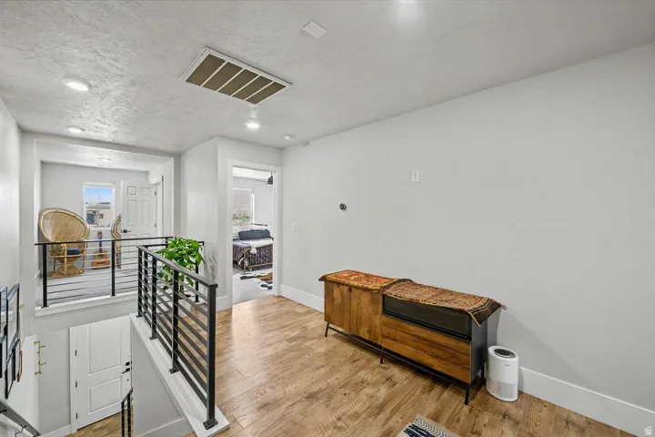 Upper-level landing featuring wood-finish flooring, recessed lighting, and a contemporary black horizontal bar railing system