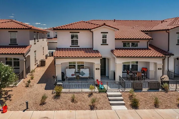 Stucco exterior townhome featuring a terracotta tile roof