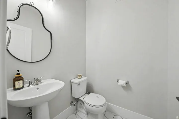 Pedestal sink with chrome faucet, complemented by a decorative black-framed mirror