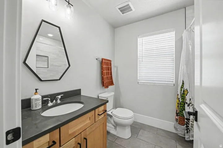 Bathroom featuring a wood vanity with dark countertop, undermount sink, and dual-handle faucet