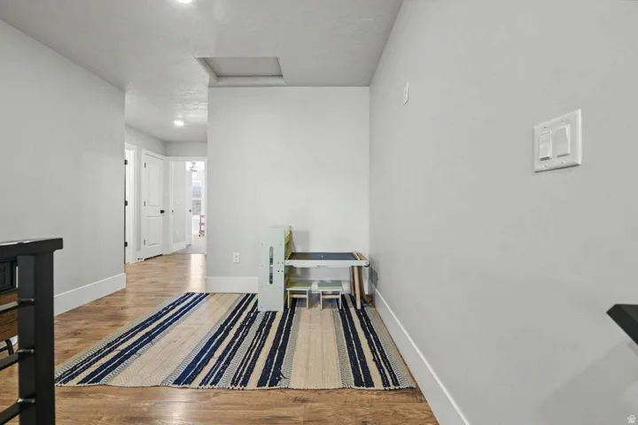 Hallway featuring wood-finish flooring, light grey walls, white trim, and recessed lighting