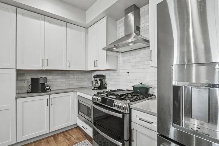 Modern kitchen featuring white shaker-style cabinetry, a subway tile backsplash, and stainless steel appliances
