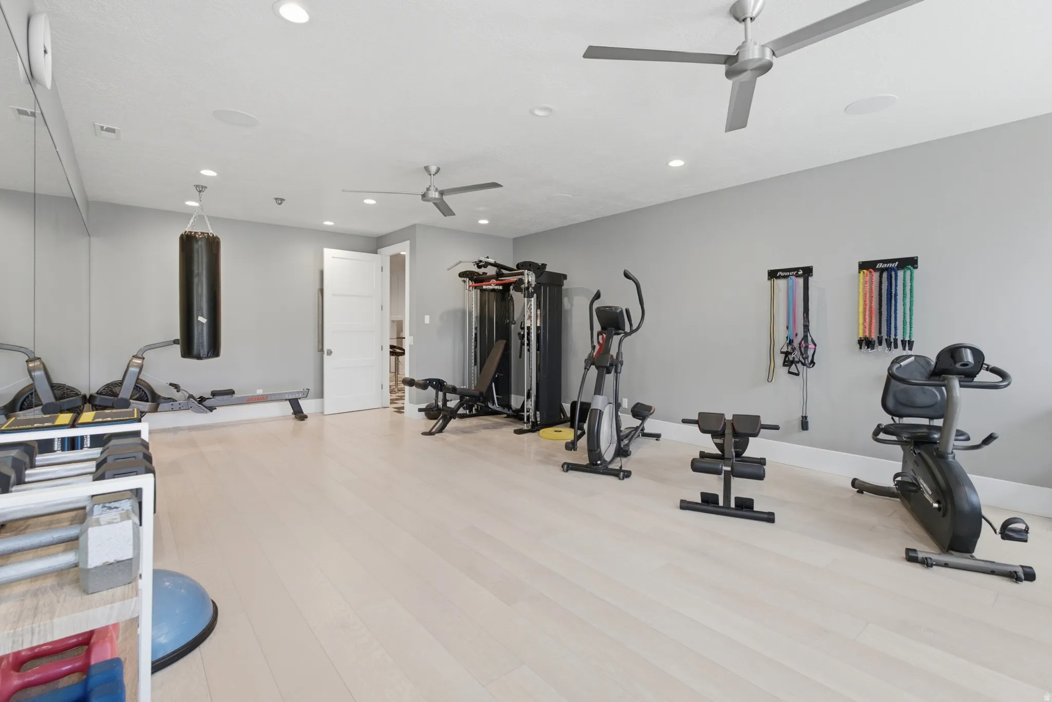 Spacious interior room featuring light wood-finish flooring, recessed lighting, and two ceiling fans