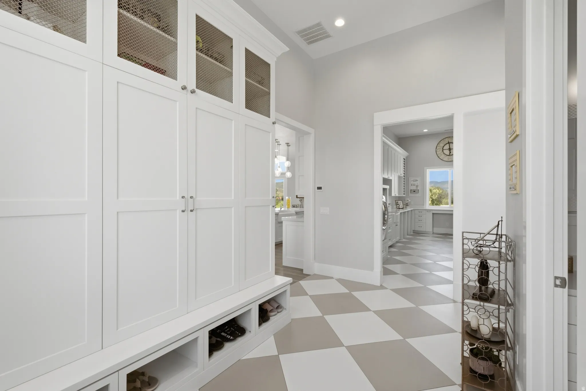 Built-in white cabinetry with wire mesh upper doors and lower cubbies provides extensive storage