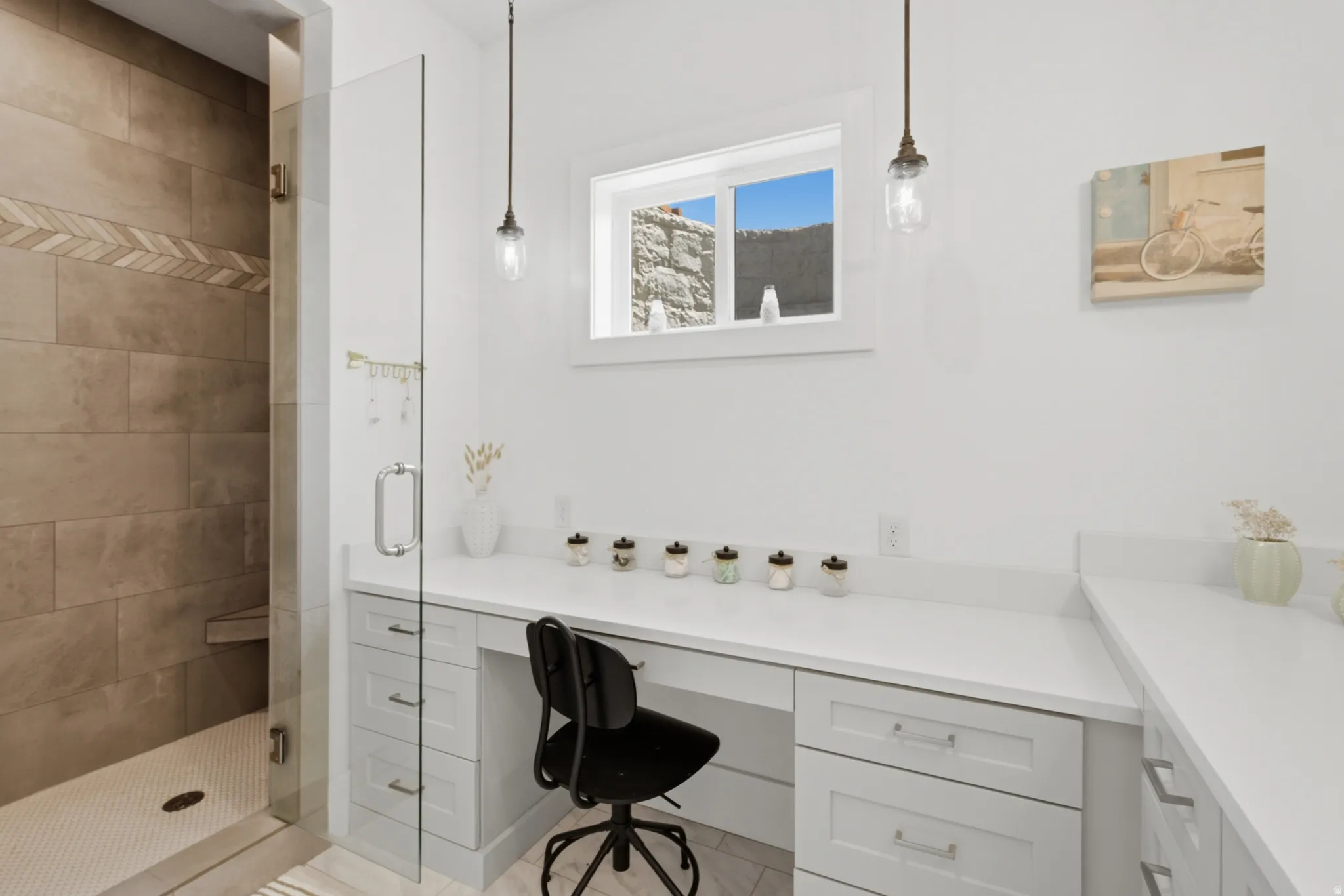 Built-in vanity with light grey shaker-style cabinetry, white countertops, and a clear glass shower enclosure