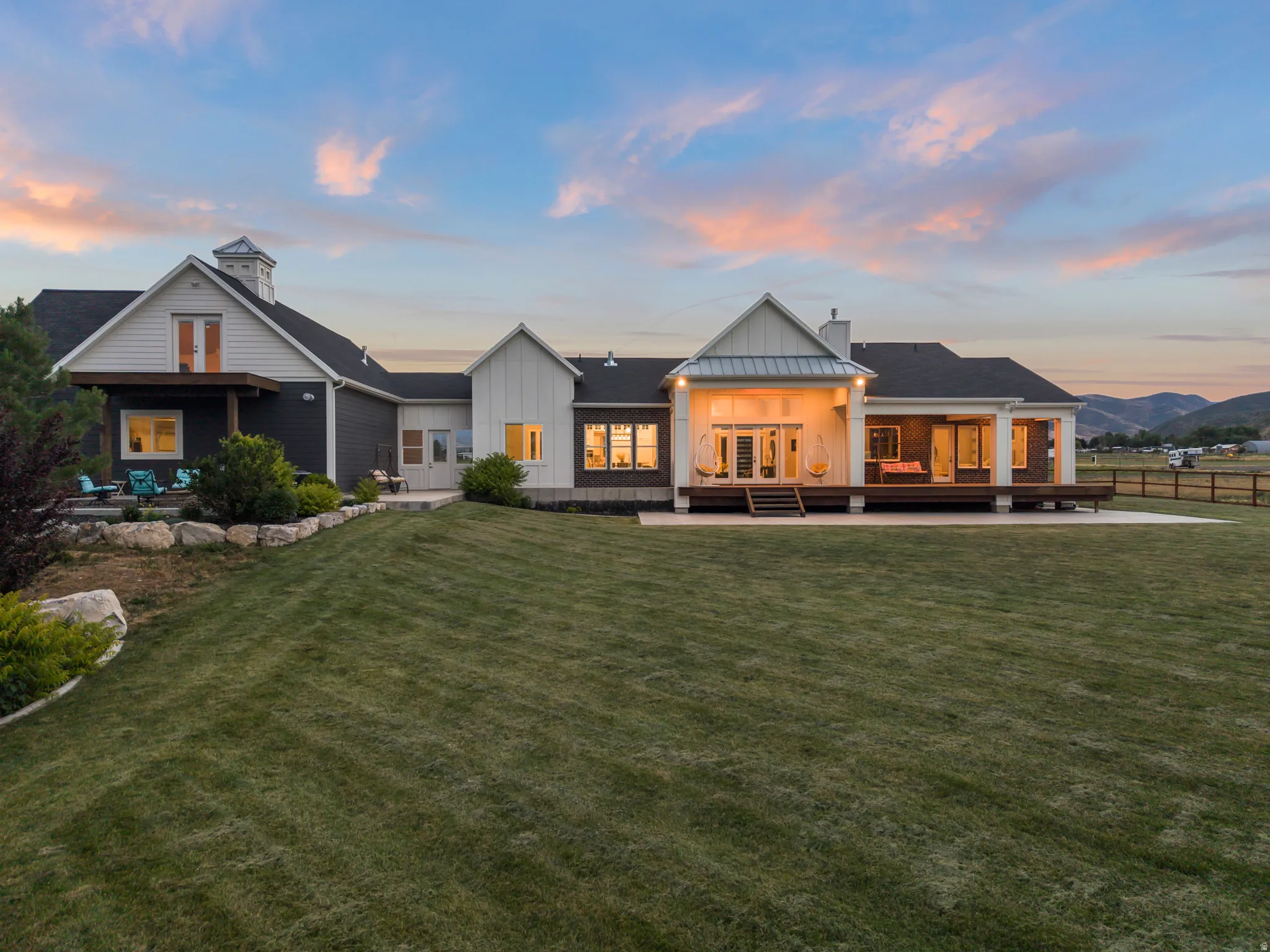 Spacious rear elevation featuring a multi-level deck, expansive patio, and large lawn area