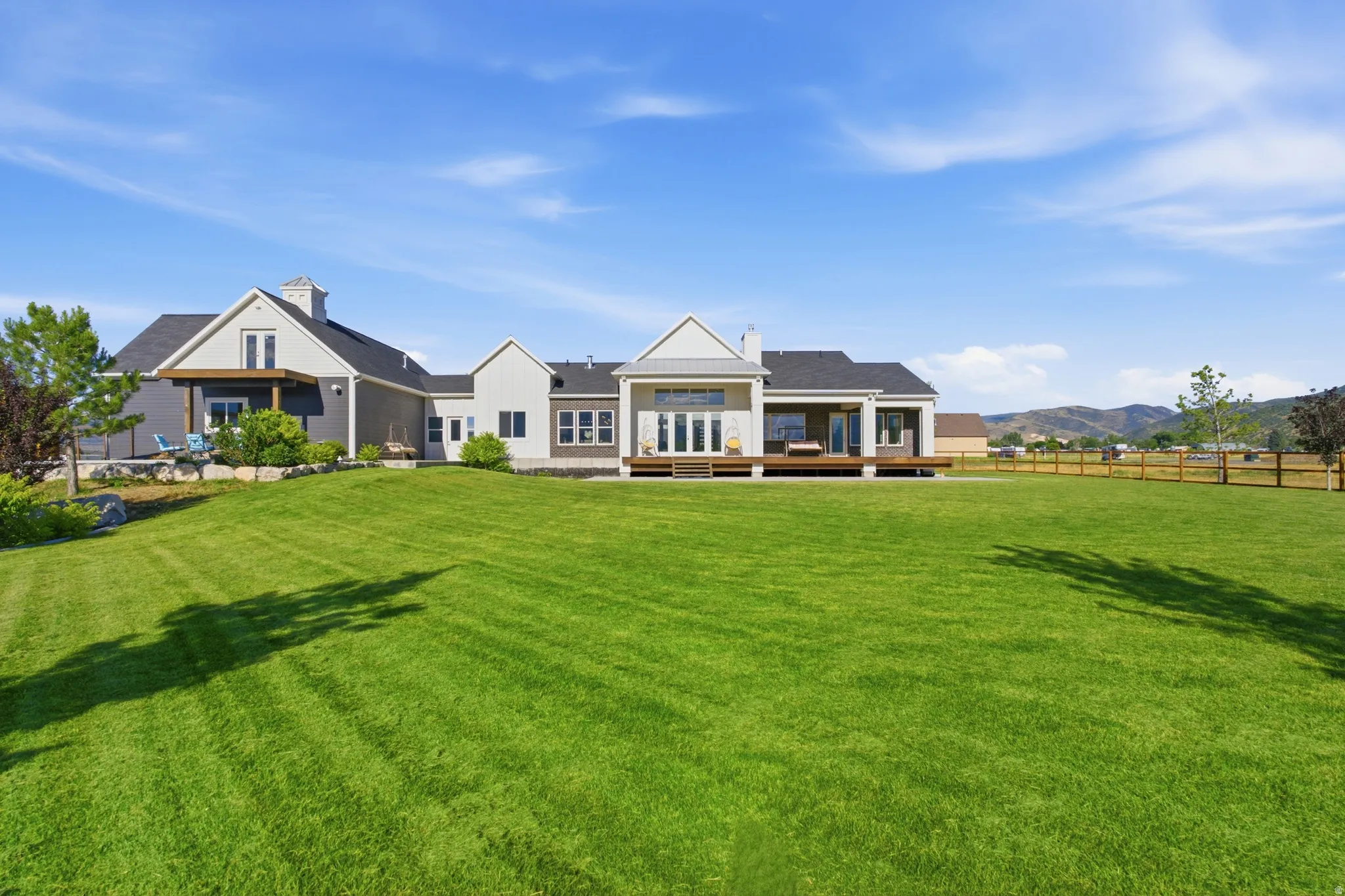 Expansive backyard featuring a manicured lawn, multiple outdoor decks, and mountain scenery