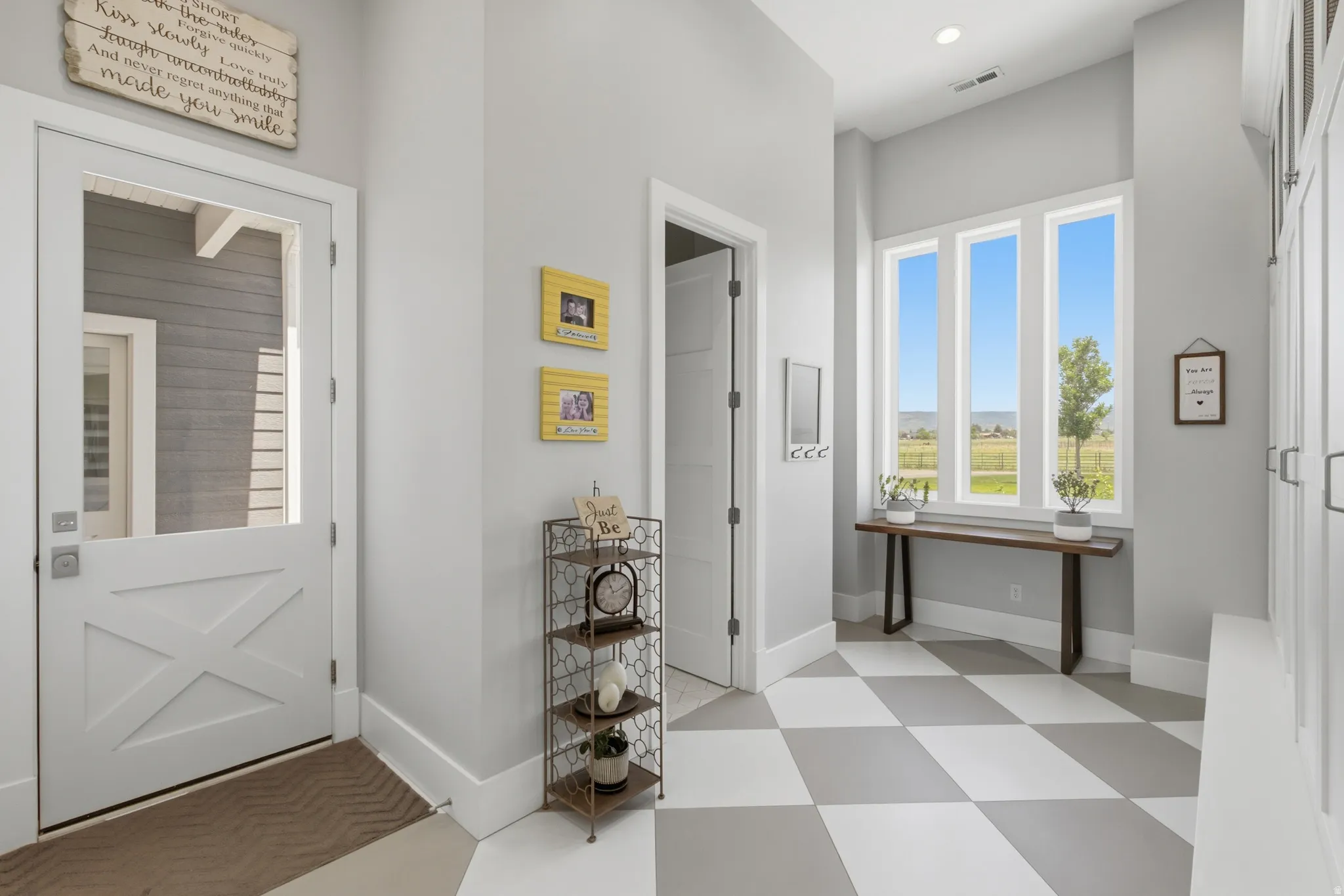 Entryway featuring a white Dutch door with clear glass panel, large picture windows, recessed lighting, and checkerboard floor tiles