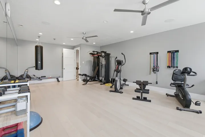 Spacious interior room featuring light wood-finish flooring, recessed lighting, and two ceiling fans