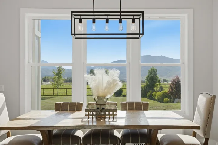 Expansive multi-pane window offering panoramic mountain scenery and green pasture