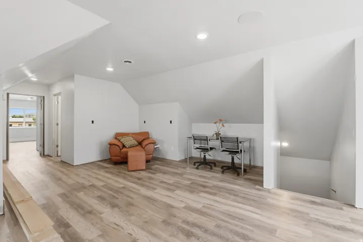 Spacious loft area featuring wood-finish flooring, recessed lighting, and a built-in ceiling speaker