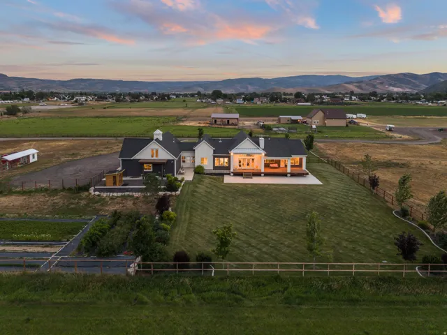 Expansive property featuring a modern farmhouse-style residence with a dark facade, light-colored accents, and a prominent covered porch