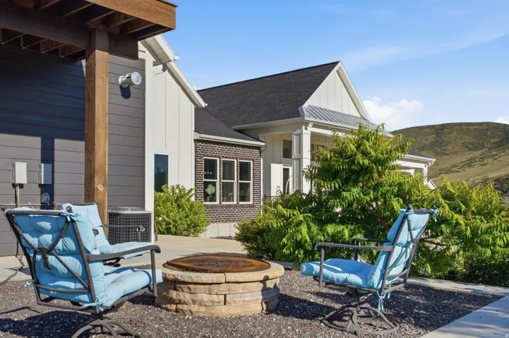 Outdoor patio featuring a built-in stone fire pit, gravel ground cover, and a partial view of the residence
