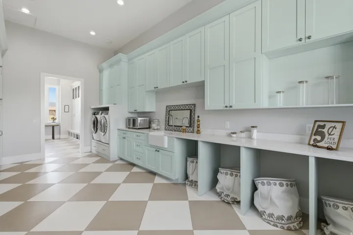 Laundry room featuring extensive light blue cabinetry, built-in utility sink, and white countertops