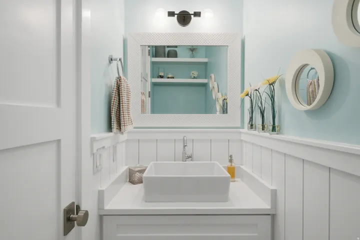 Powder room featuring board and batten wainscoting, a rectangular vessel sink, and a framed mirror