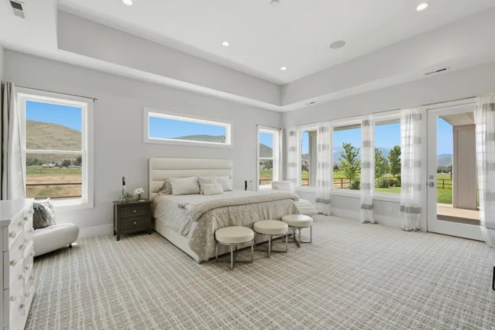 Spacious room featuring a tray ceiling with recessed lighting, multiple large windows, and a glass-paneled door opening to an outdoor area