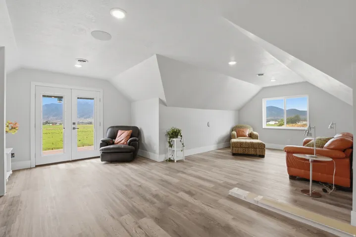 Spacious loft area featuring wood-finish flooring, recessed lighting, and white baseboards