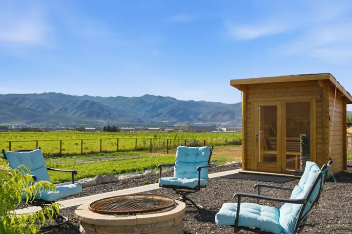 Outdoor sauna with double glass doors and a stone fire pit area