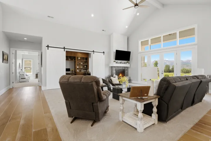 Vaulted ceilings highlight this living space, featuring a corner fireplace with a dark tile surround and a crisp white mantel