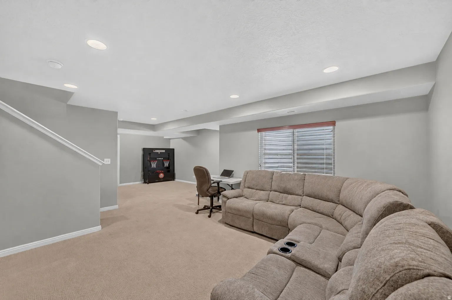 Spacious bonus room featuring neutral carpeting, recessed lighting, and a white handrail
