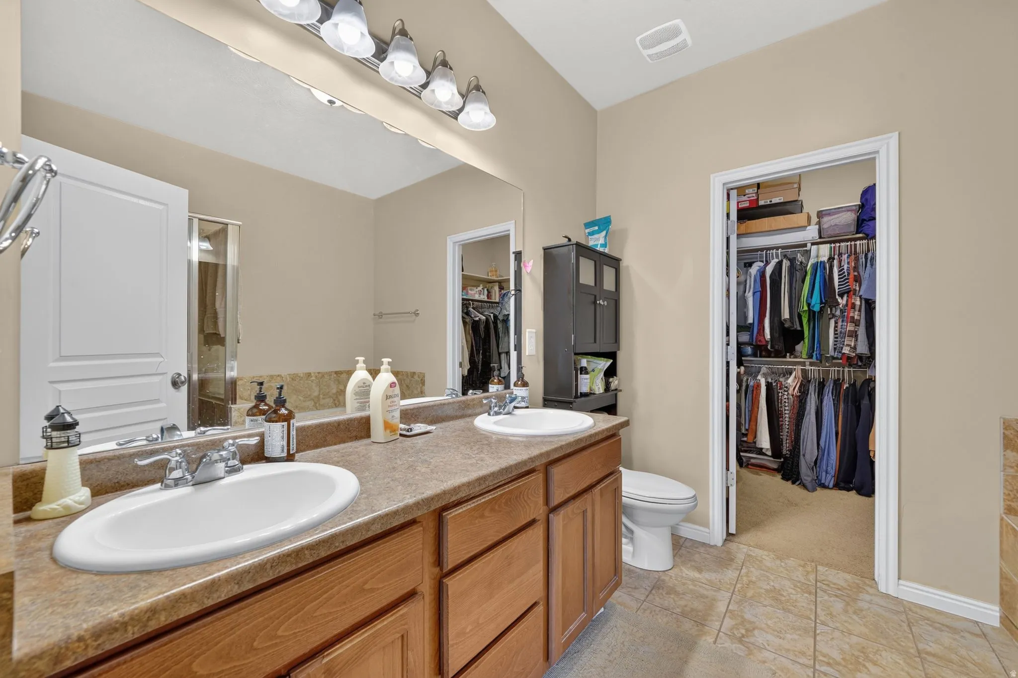 Bathroom featuring a double vanity with wood-finish cabinetry and a spacious mirror