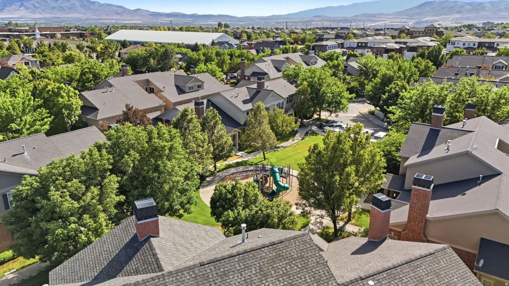 Community green space featuring a playground and mature trees