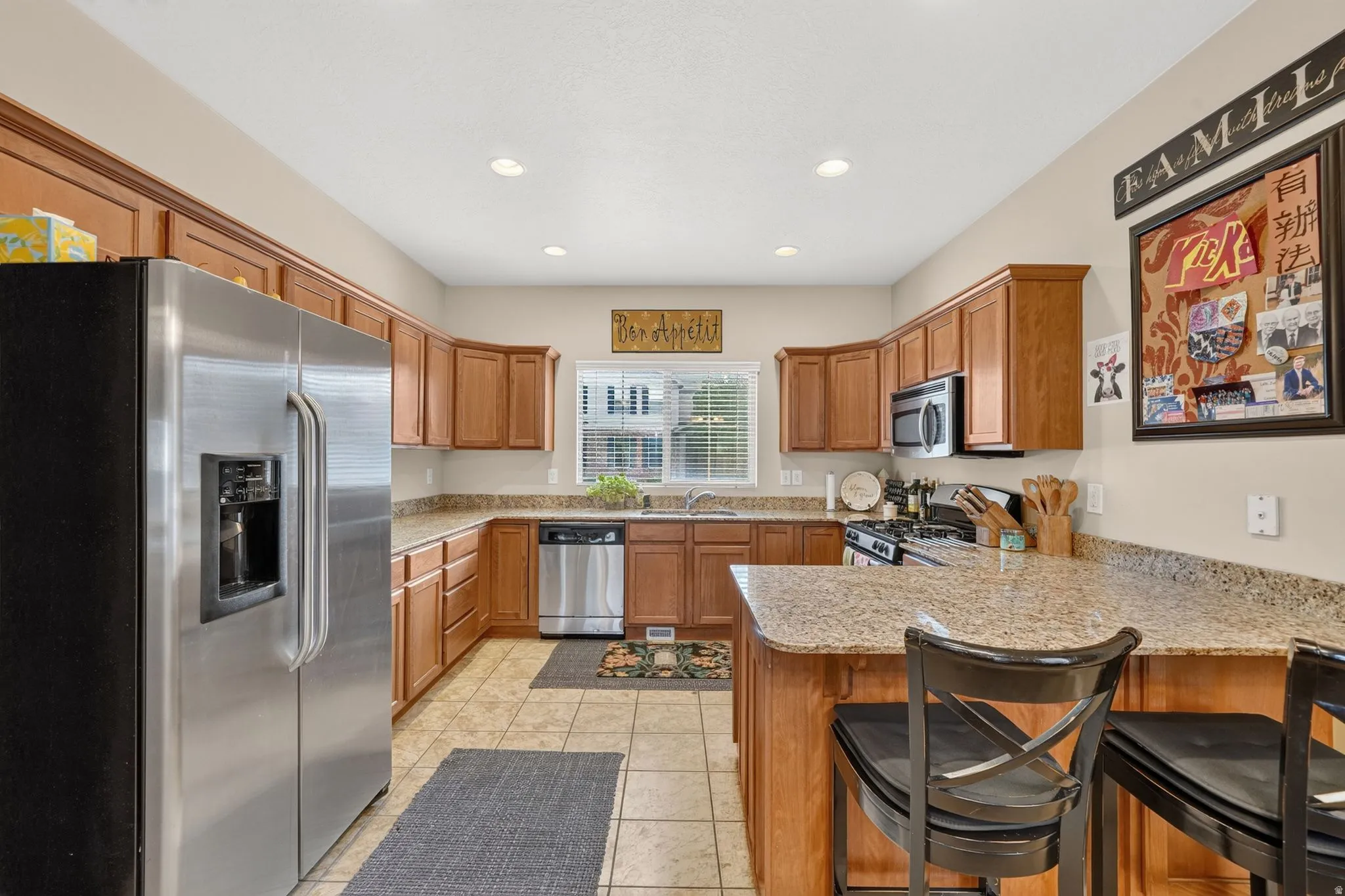 Kitchen featuring wood cabinetry, stainless steel appliances, speckled countertops, and tile flooring