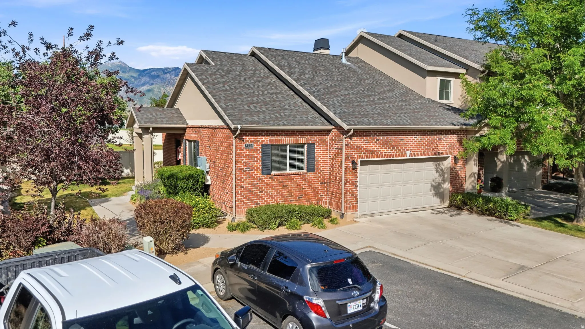 Brick exterior with a peaked roofline, attached garage, and a concrete driveway