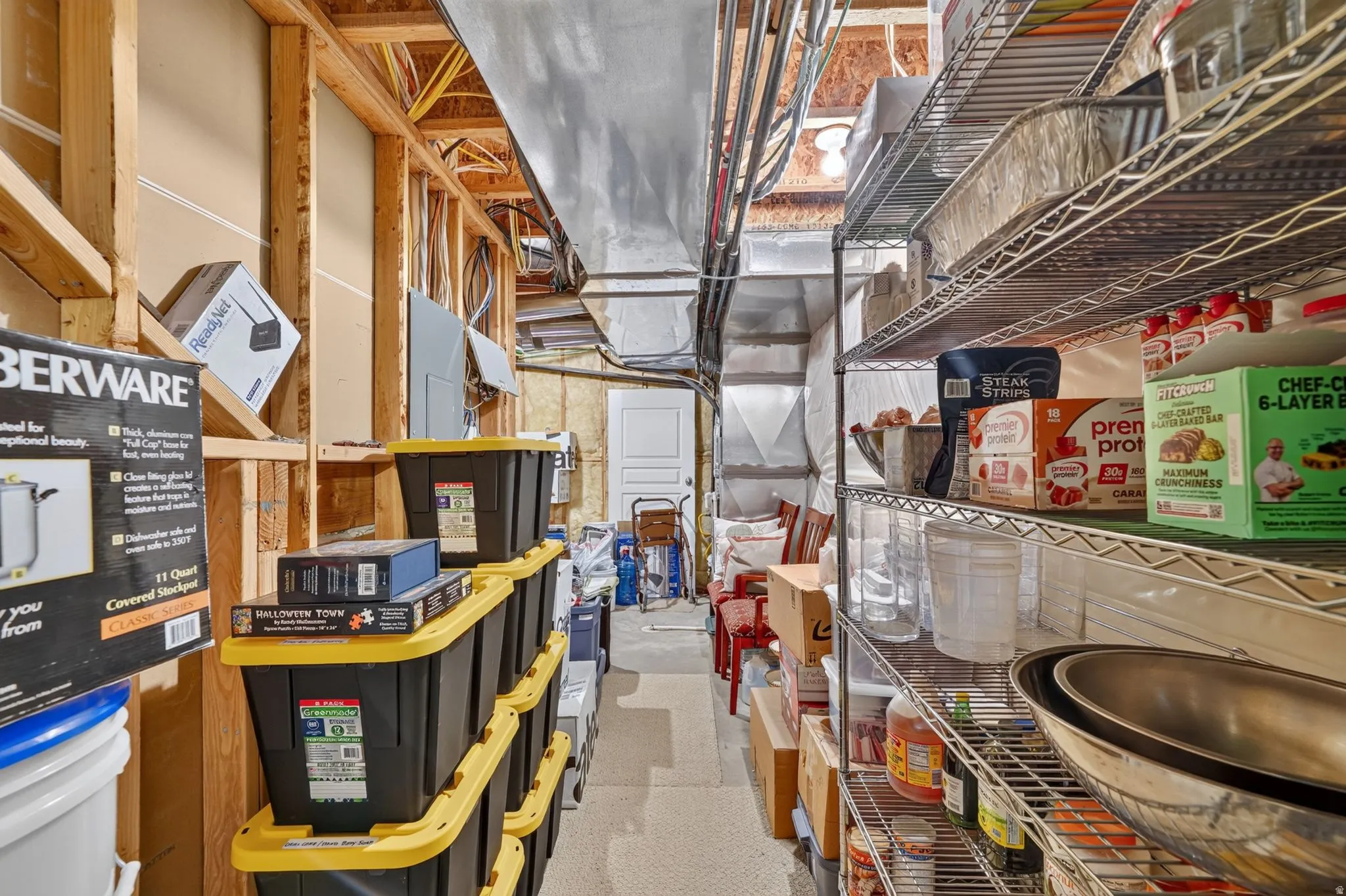 Unfinished basement area featuring exposed wood framing, ductwork, and electrical conduit, providing substantial storage capacity with built-in metal shelving