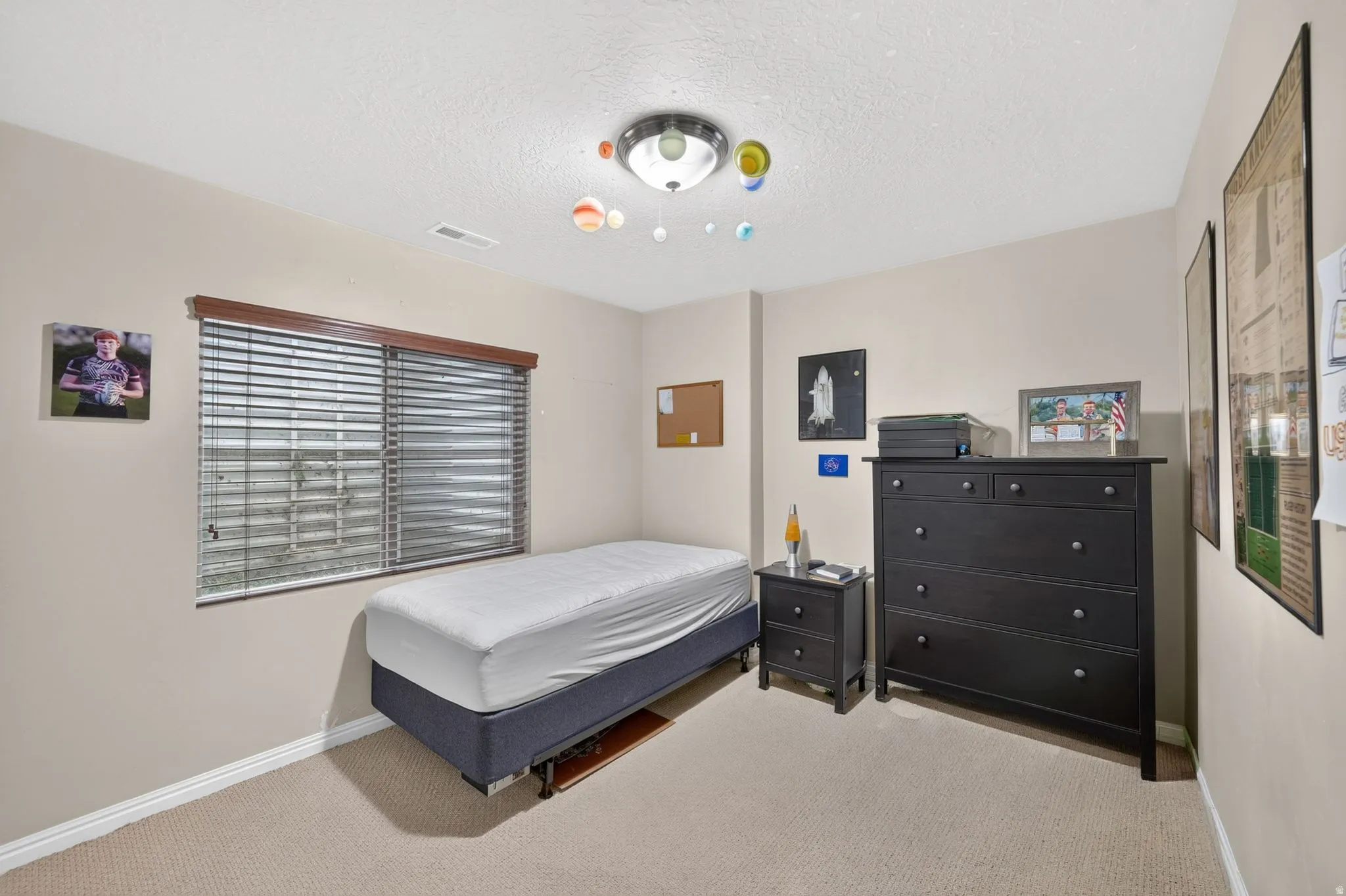 Carpeted room featuring a window with horizontal blinds and a wood valance