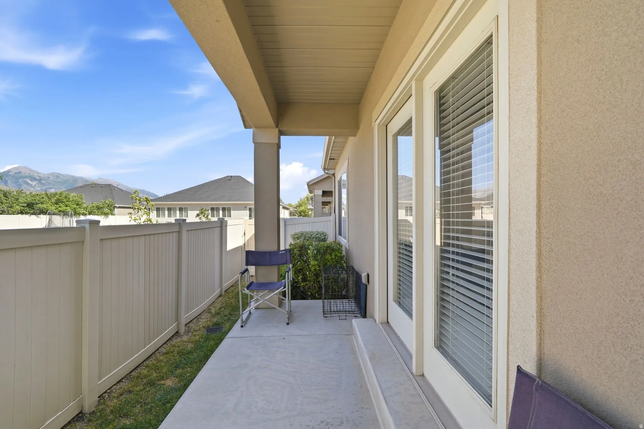 Covered patio featuring concrete flooring, a stucco exterior, and dual glass panel doors with horizontal blinds
