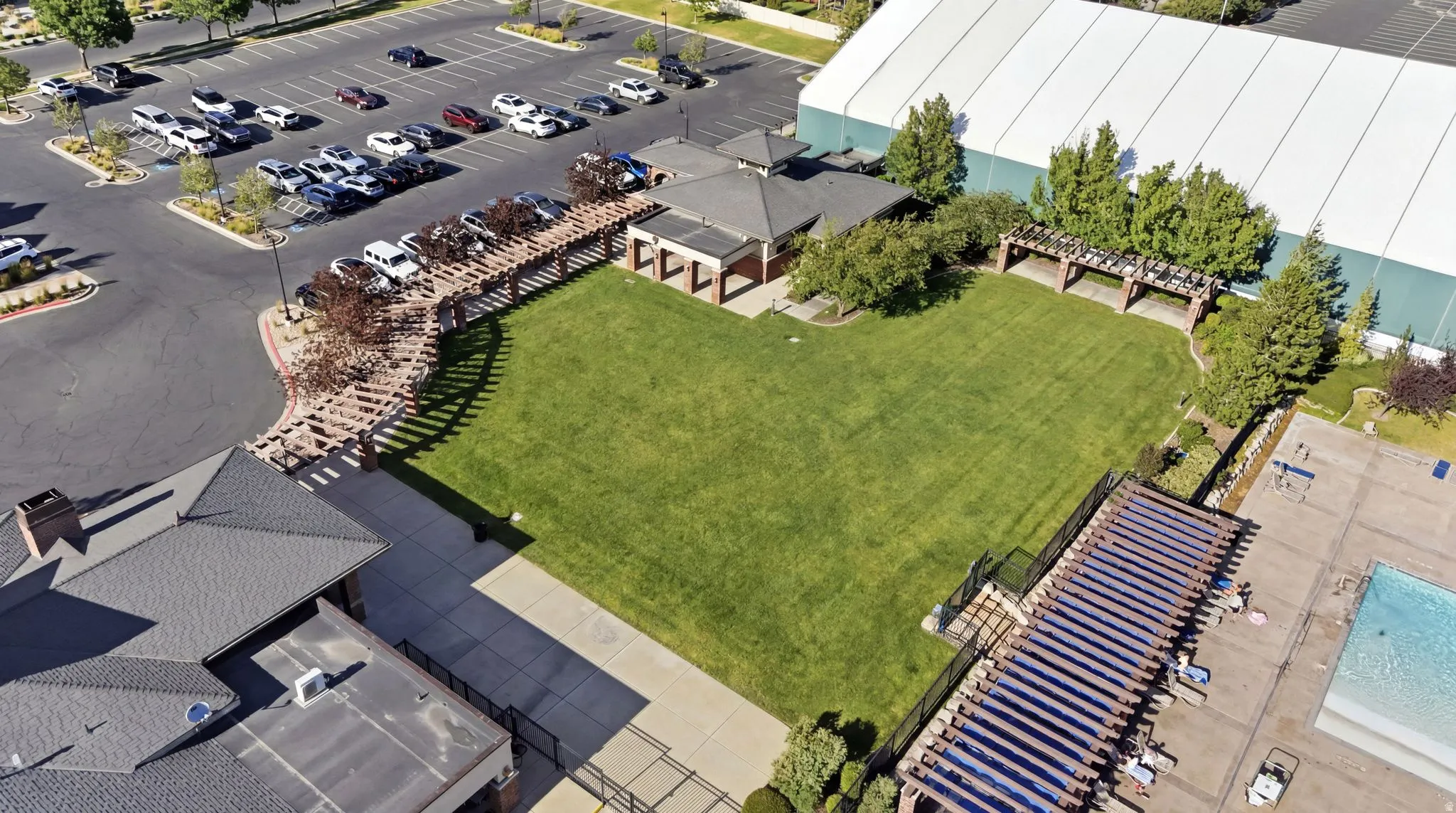 Expansive green space featuring a large lawn area, covered outdoor structures, and a dedicated parking lot