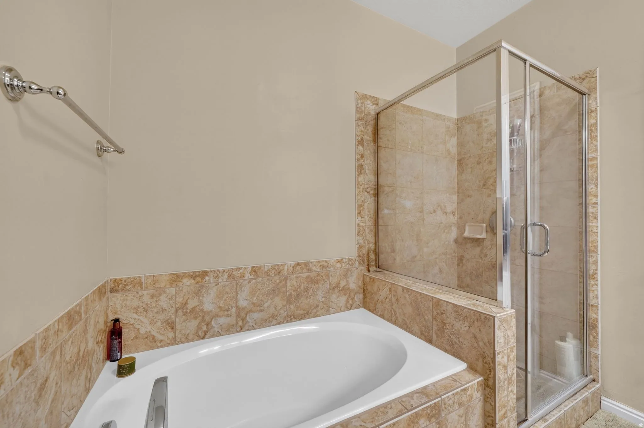 Bathroom featuring a built-in soaking tub with surrounding tile, a glass-enclosed shower with tiled walls, and polished chrome fixtures