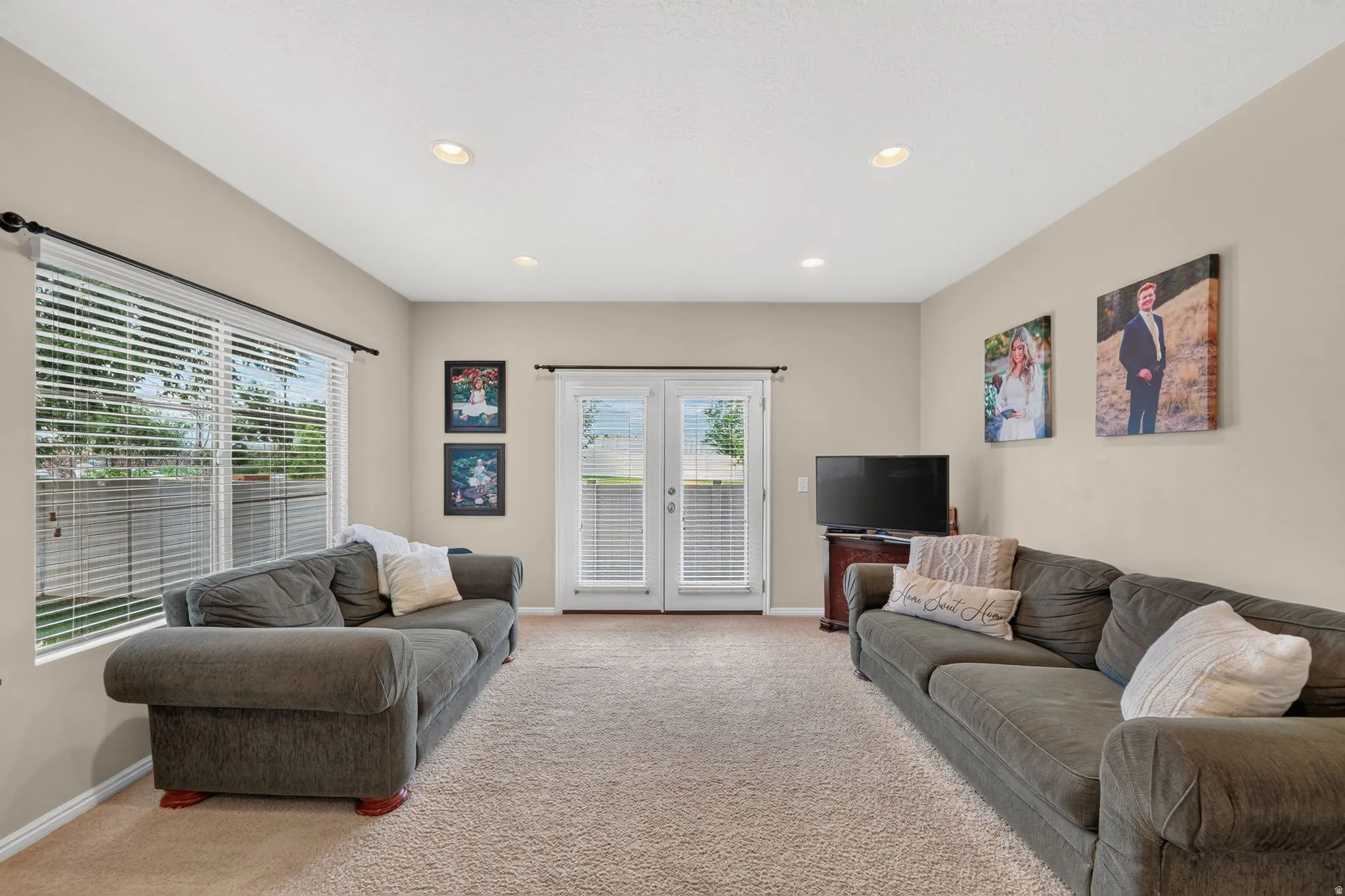 Carpeted living area featuring recessed lighting, a large window with blinds, and French doors