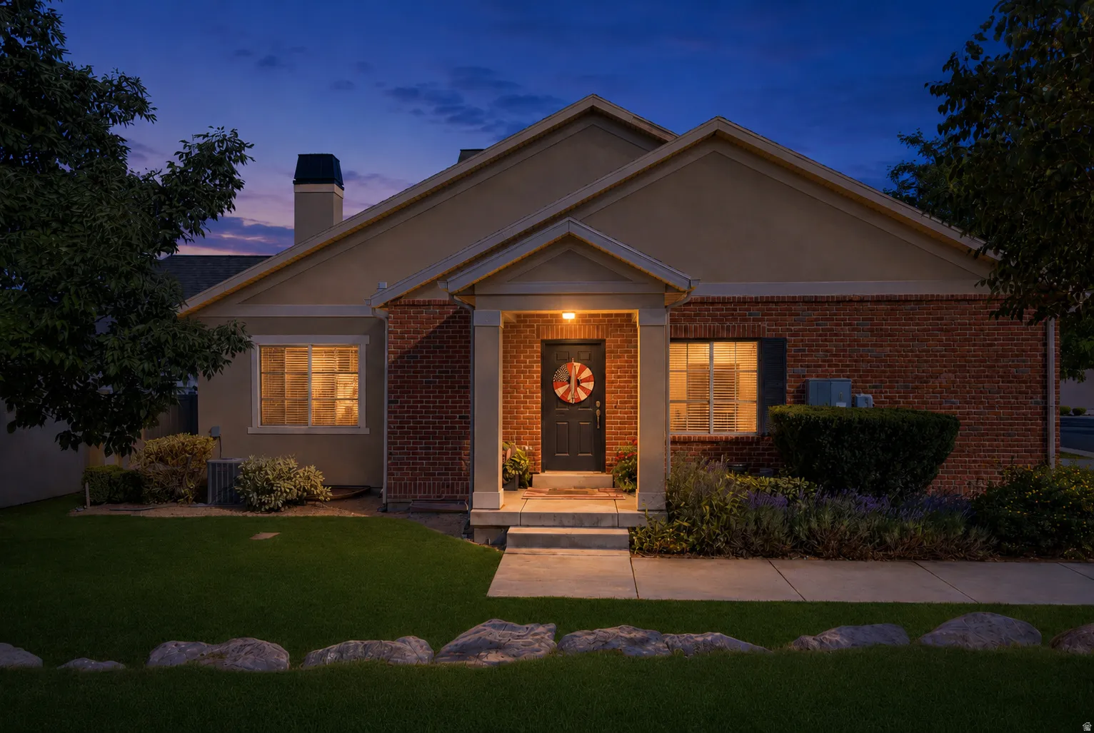 Traditional-style residence featuring a brick facade, stucco siding, and a covered porch entry