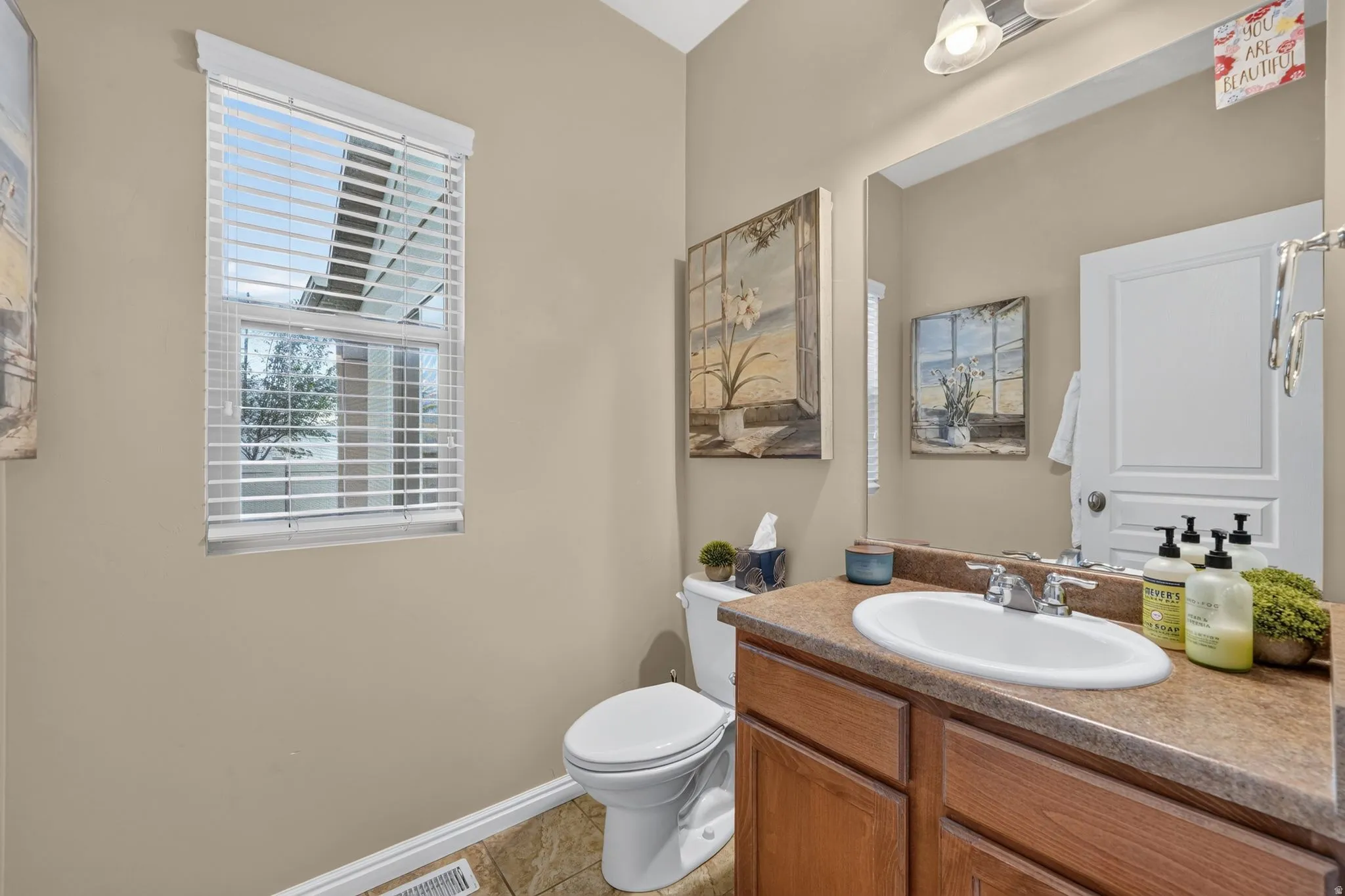 Bathroom featuring a single vanity with wood-finish cabinetry, a white oval sink, and a brown countertop