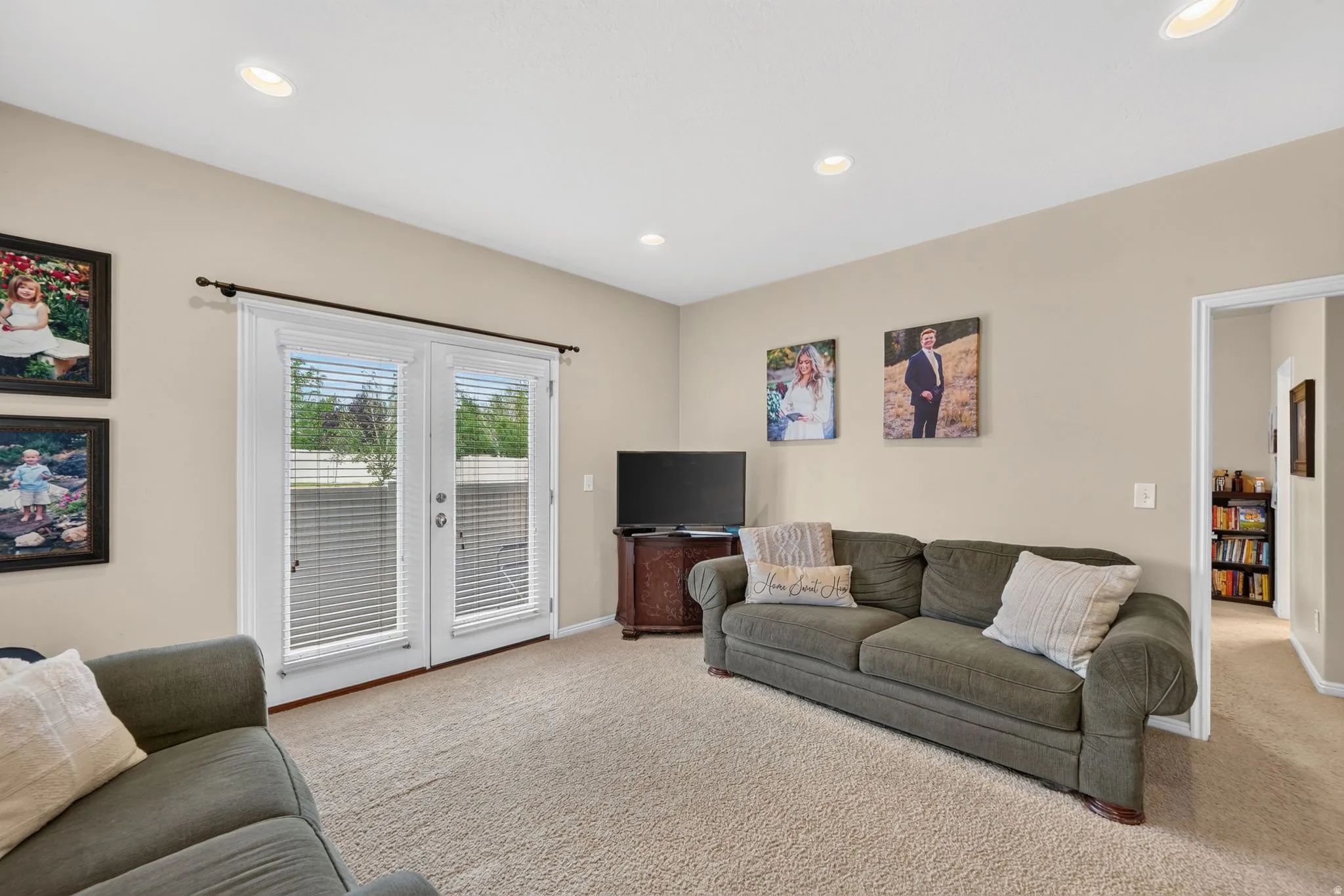 Living area featuring light beige wall paint, recessed ceiling lighting, and carpet flooring
