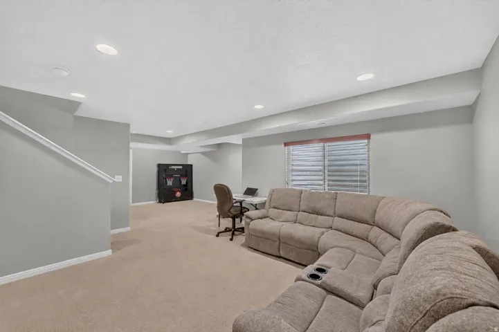Spacious bonus room featuring neutral carpeting, recessed lighting, and a white handrail