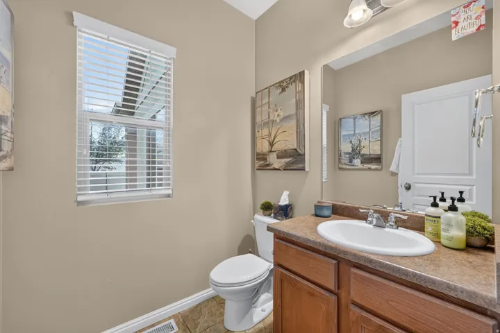 Bathroom featuring a single vanity with wood-finish cabinetry, a white oval sink, and a brown countertop
