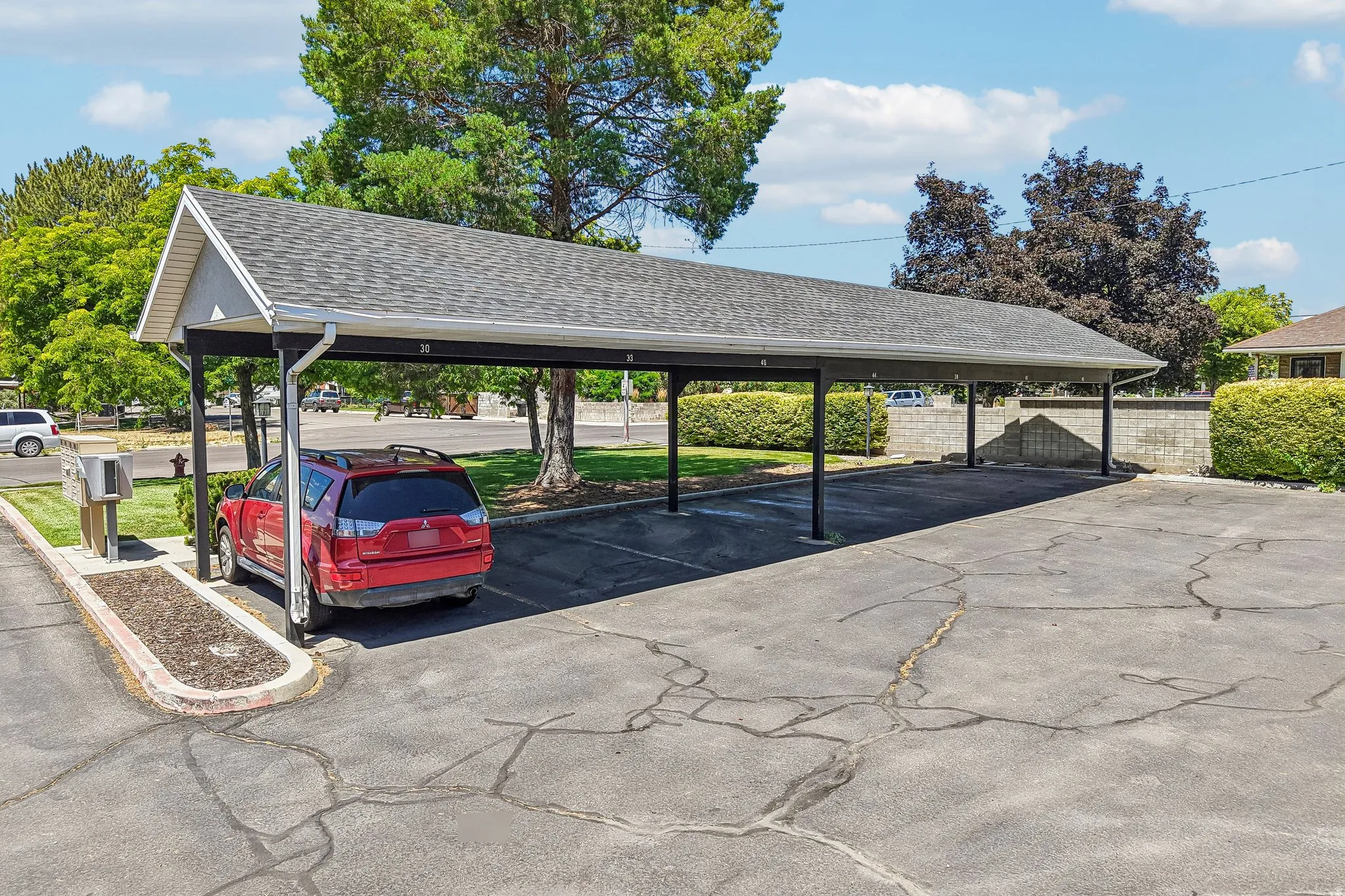 Carport structure featuring a gabled roof with asphalt shingles, metal support posts, and integrated rain gutters