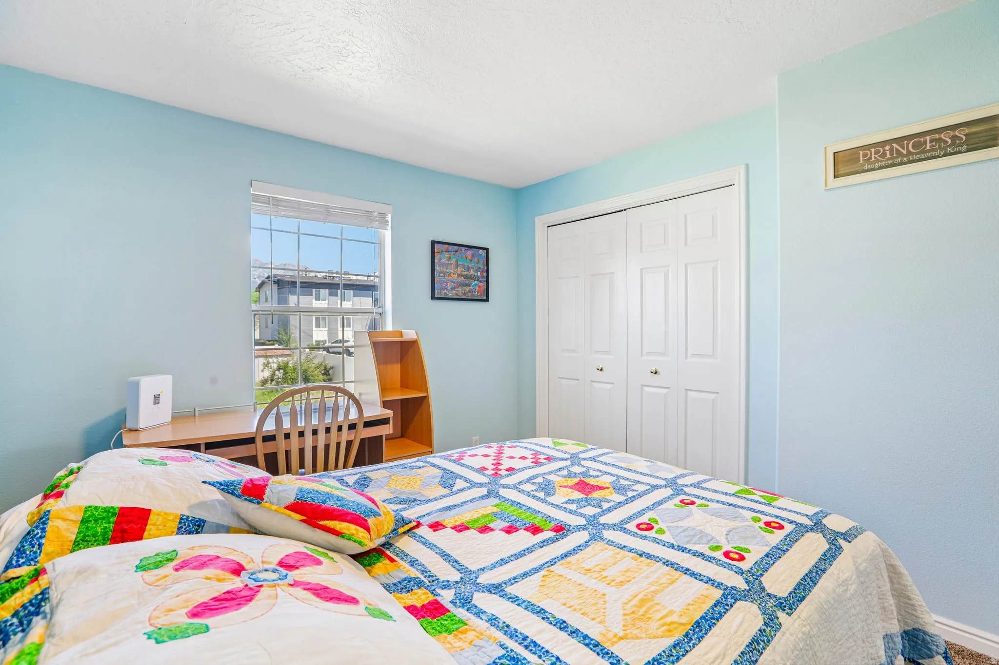Interior room featuring light blue walls, a window with horizontal blinds, and a built-in desk with shelving