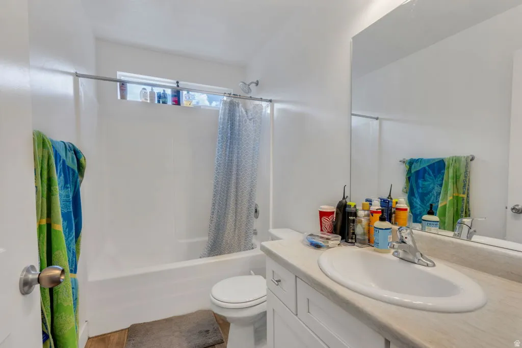 Bathroom featuring a white vanity with an integrated sink, a large wall-mounted mirror, and a full-size bathtub with an overhead shower