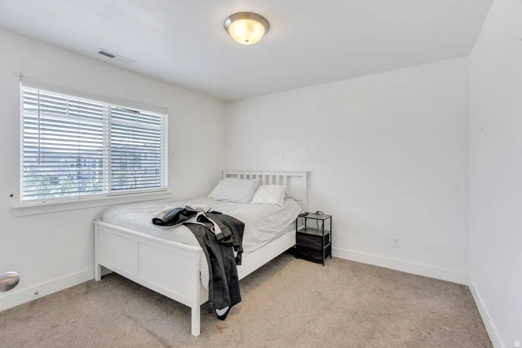 Room featuring neutral carpet flooring, white painted walls, and a single window with horizontal blinds
