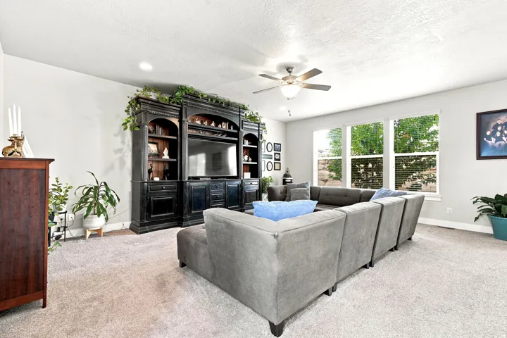 Spacious living area featuring light-colored carpeting, recessed lighting, and a ceiling fan