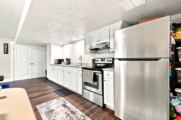Kitchenette featuring white cabinetry, wood-finish flooring, stainless steel appliances, a stainless steel sink, and recessed lighting