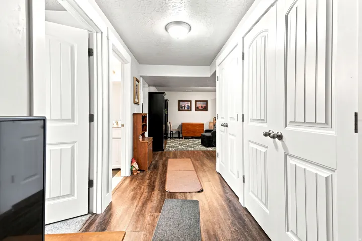 Hallway featuring wood-finish flooring, white paneled doors, brushed nickel hardware, and recessed lighting